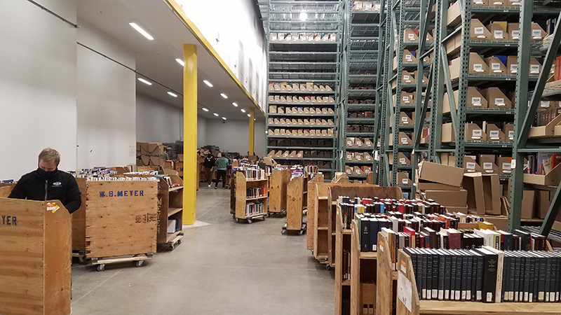 movers packing carts full of books in a warehouse type space
