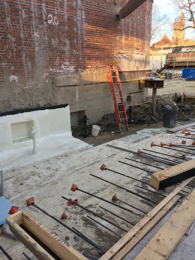 steel girder in the background that is carried on two mini piles to temporarily support the end of the 1909 west pavilion wall