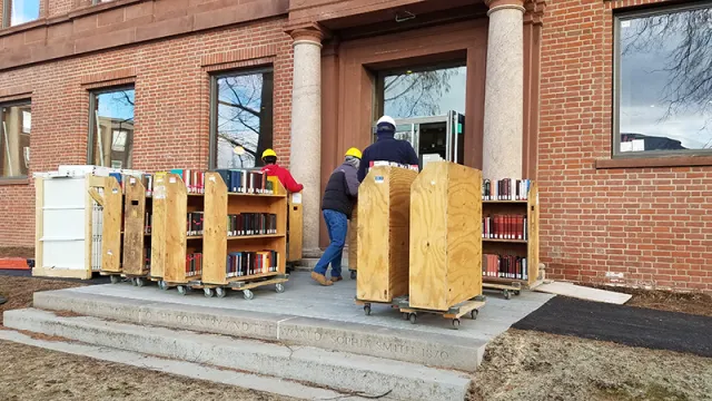 workers line up carts full of books outside the Neilson Library