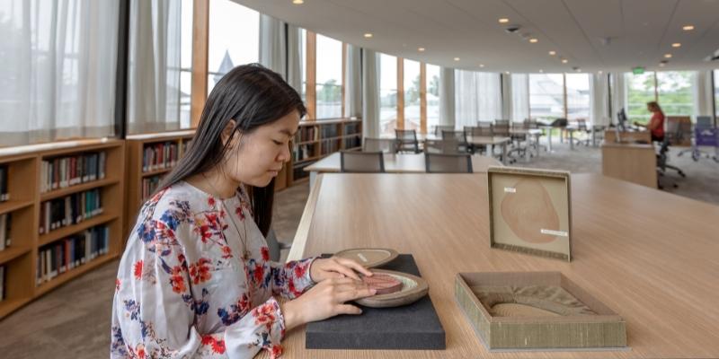 a student with long hair touching a rare book object